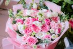 A beautiful bouquet of pink and white roses and carnations with greenery.